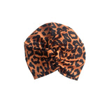 Patterned orange and black twist turban hat for women.