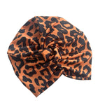 Patterned orange and black twist turban hat for women.