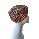 Patterned orange and black twist turban hat for women.