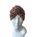 Patterned orange and black twist turban hat for women.