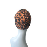 Patterned orange and black twist turban hat for women.